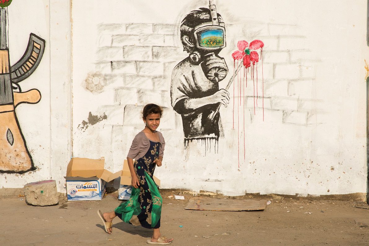 An Iraqi girl walks past a mural during ongoing protest