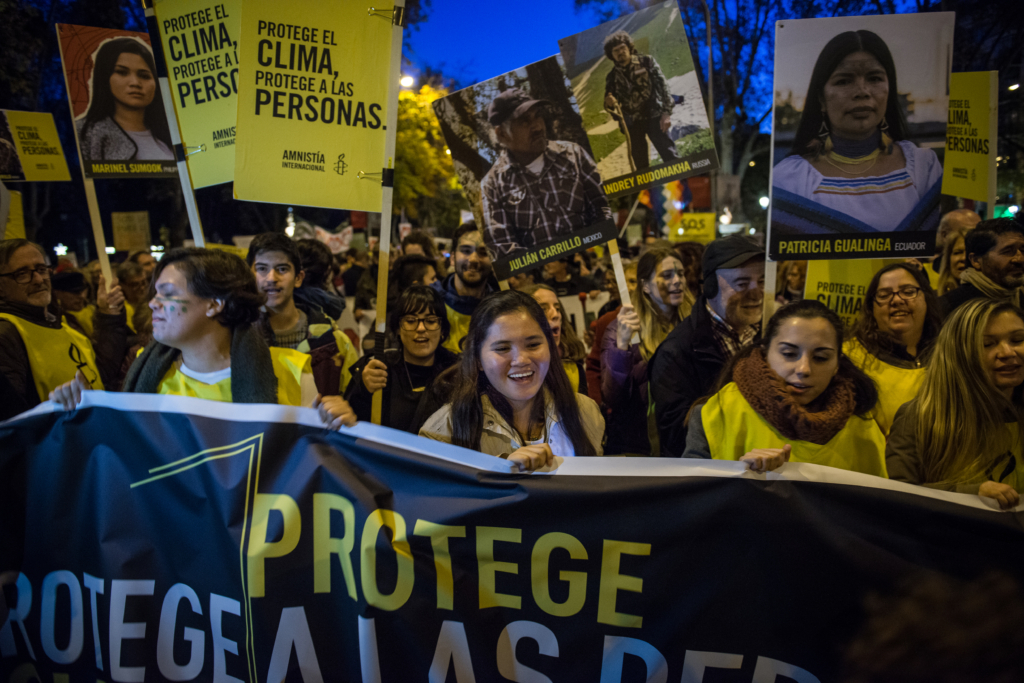 一群国际特赦组织活动人士举着标语和公告牌，身穿黄、白和黑色衬衫，为我们拥有安全和健康星球的权利而抗议。 