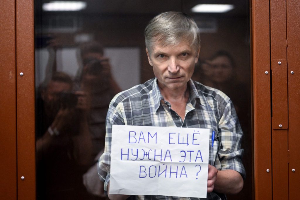 Moscow city deputy Alexei Gorinov, accused of spreading "knowingly false information" about the Russian army fighting in Ukraine, stands with a poster reading ""Do you still need this war?" inside a glass cell during the vedict hearing in his trial at a courthouse